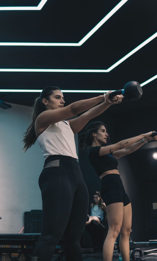 Dos chicas en el gimnasio sujetando una kettlebell Dos chicas entrenando